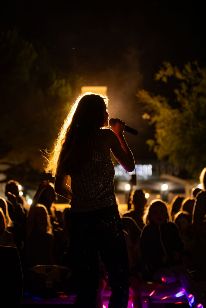 Silhouette d’artiste sur scène face au public, atmosphère nocturne et lumière dramatique