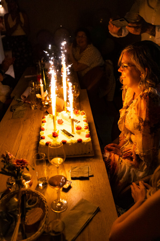 Célébration d’anniversaire en intérieur avec gâteau et bougies, photographie d’événement intime et chaleureux.