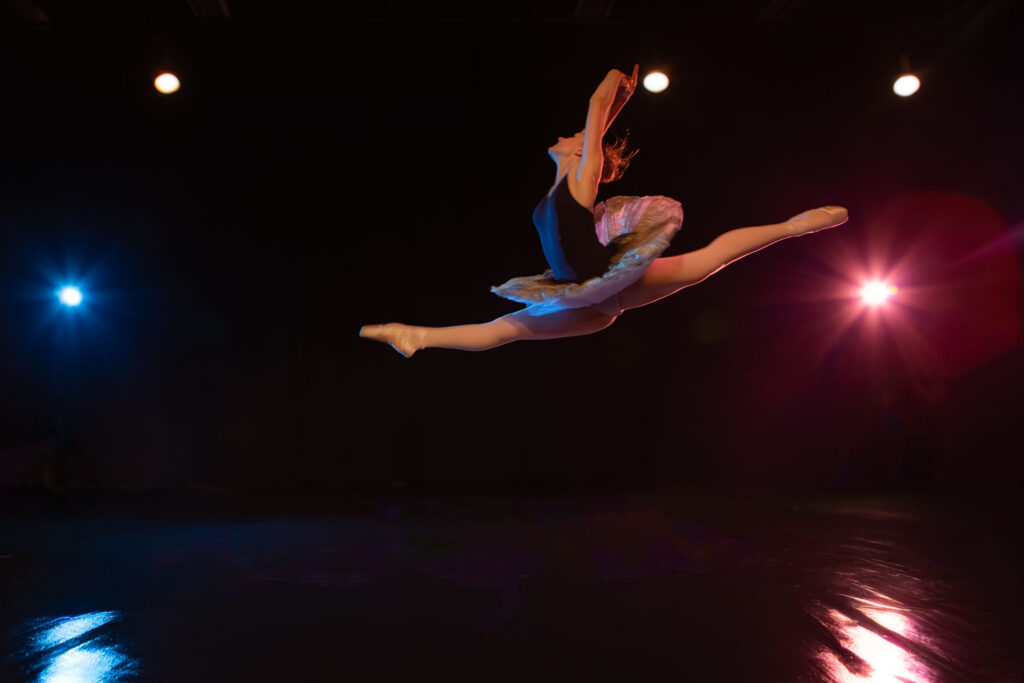 Photographie de danse artistique avec mouvement ample et éclairage scénique contrasté.