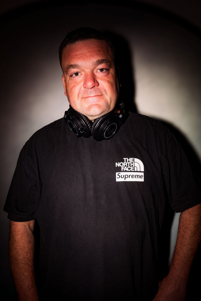 Portrait studio sur fond sombre, posture détendue et expression authentique.