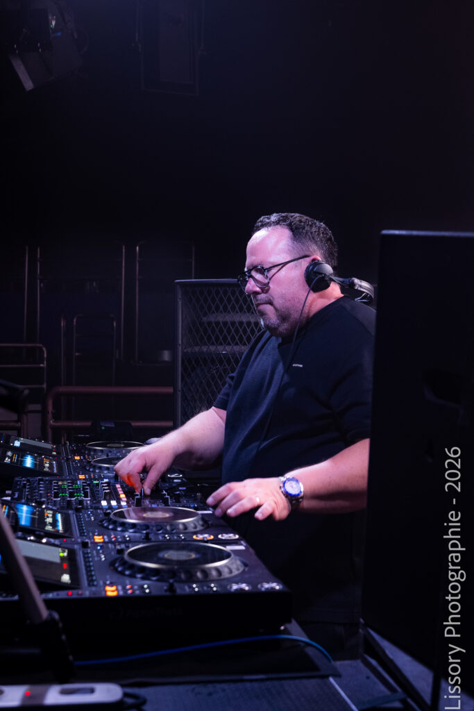 DJ concentré mixant sur des platines Pioneer de nuit dans la cabine sombre d'un club de techno.