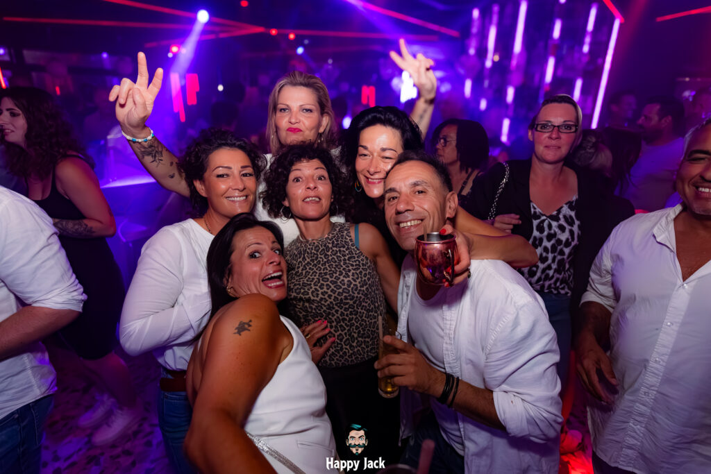 Portrait de groupe souriant sur le dancefloor d'un club de musique électronique durant une soirée