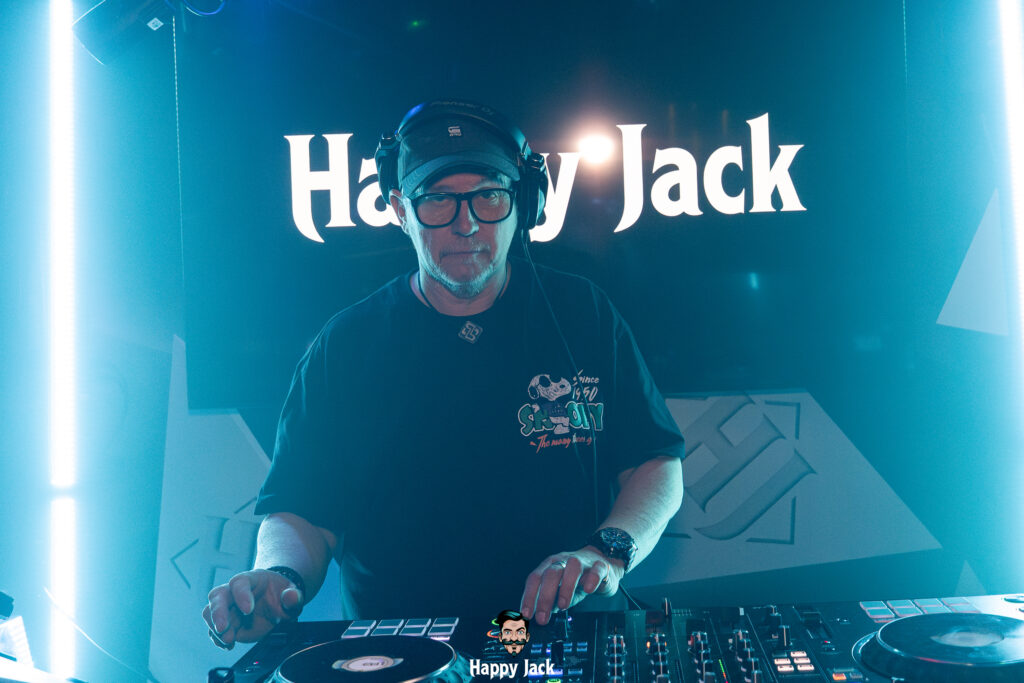DJ aux platines devant l'enseigne lumineuse néon du club Happy Jack pour l'enregistrement d'une interview BeatLines.