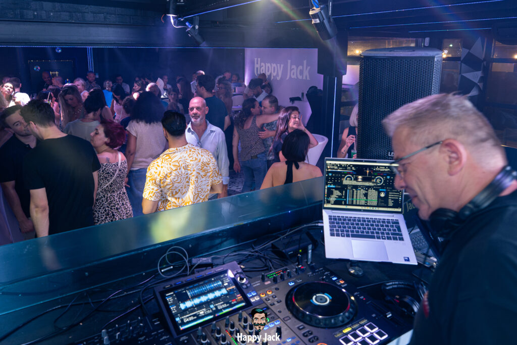 Vue panoramique depuis la régie DJ sur la piste de danse remplie et l'ambiance nightlife d'un club.